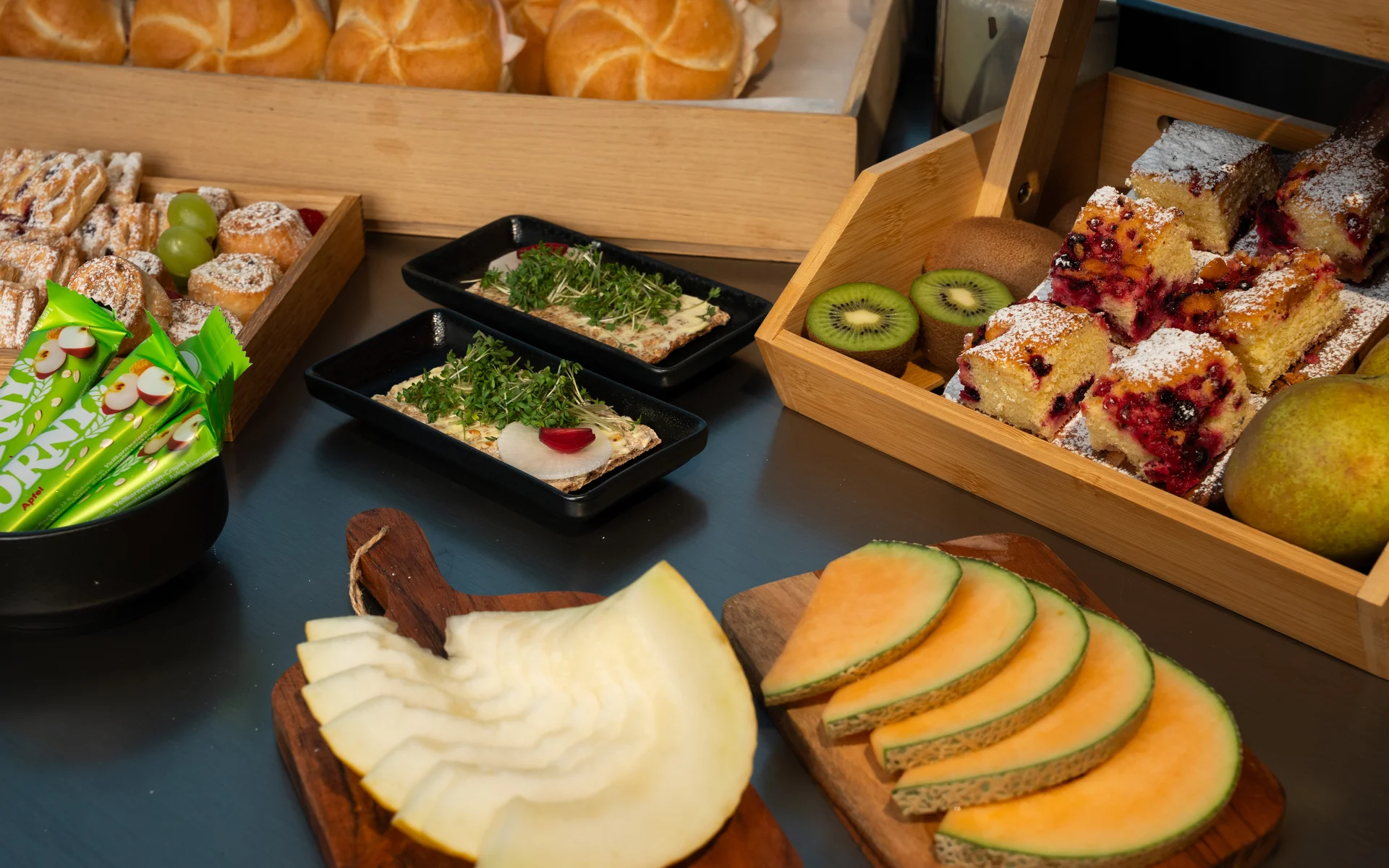 Verschiedene Brote, Kuchenstücke, frisches Obst und Snacks auf Holzbrettern