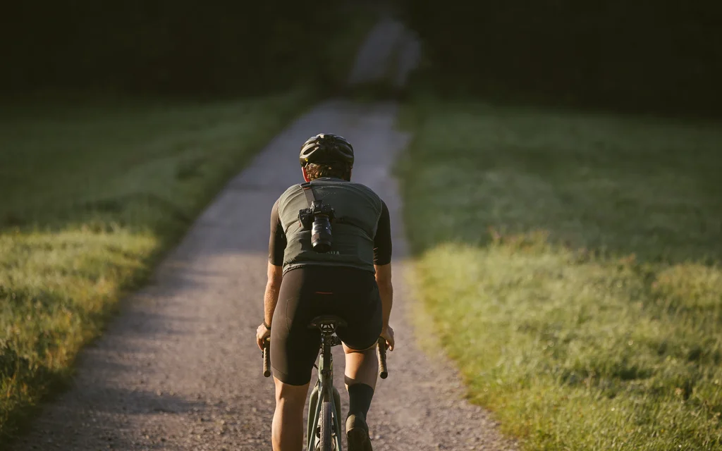 Fahrradfahrer auf schmalem Weg umgeben von Wiese bei Sonnenlicht