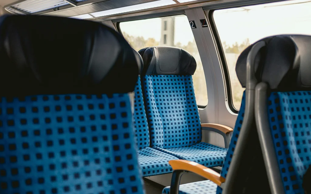 Leere blaue Sitzplätze mit schwarzen Kopfstützen in einem Zugabteil