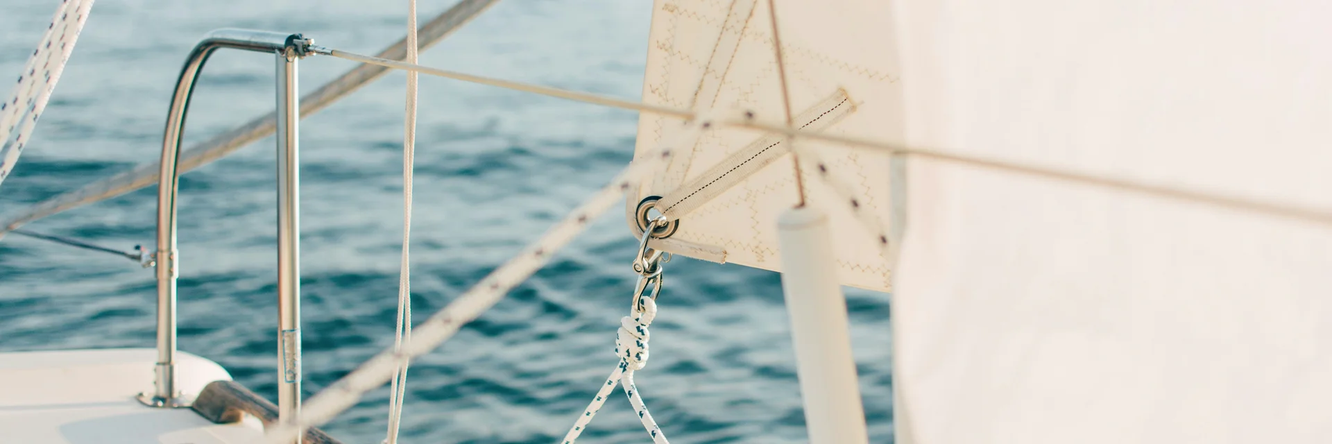 Segeln, Kitesurfen & Co. am Neusiedler See Nahaufnahme eines weißen Segels und Takelage auf einem Segelboot auf dem Wasser