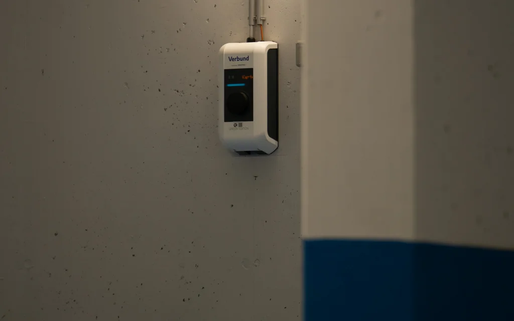 Wandmontierte Verbund-Ladestation in einer Parkgarage mit blauen und grauen Wänden