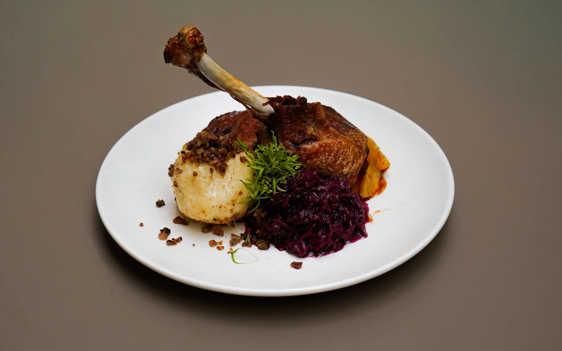 Ankkuri: Our restaurant near Parndorf Roasted goose leg with dumpling, red cabbage, and sauce on a white plate