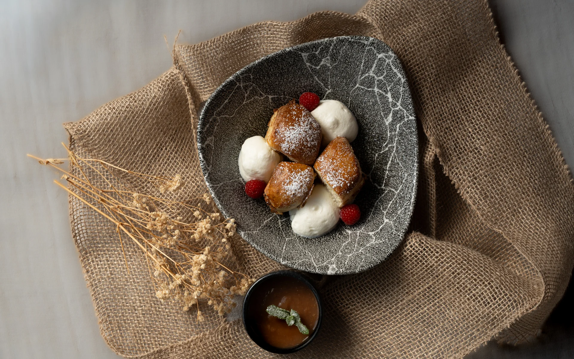 Dessert mit Sahne, Beeren und Sauce auf strukturierter Stoffunterlage