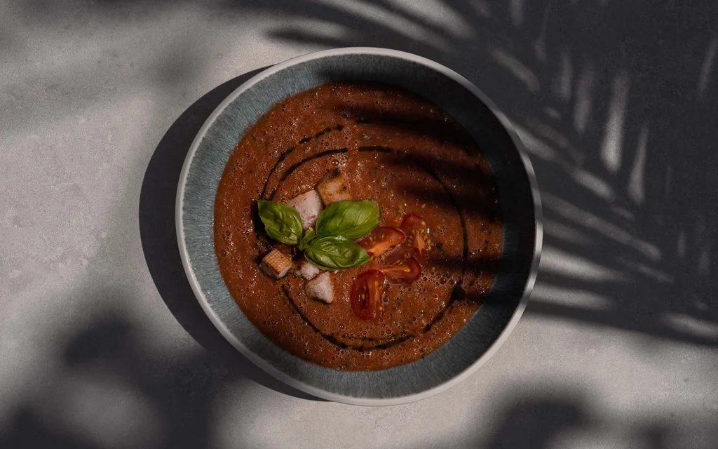 The NILS am See: the adults-only boutique hotel Tomato soup with croutons and basil in bowl, plant shadows on surface