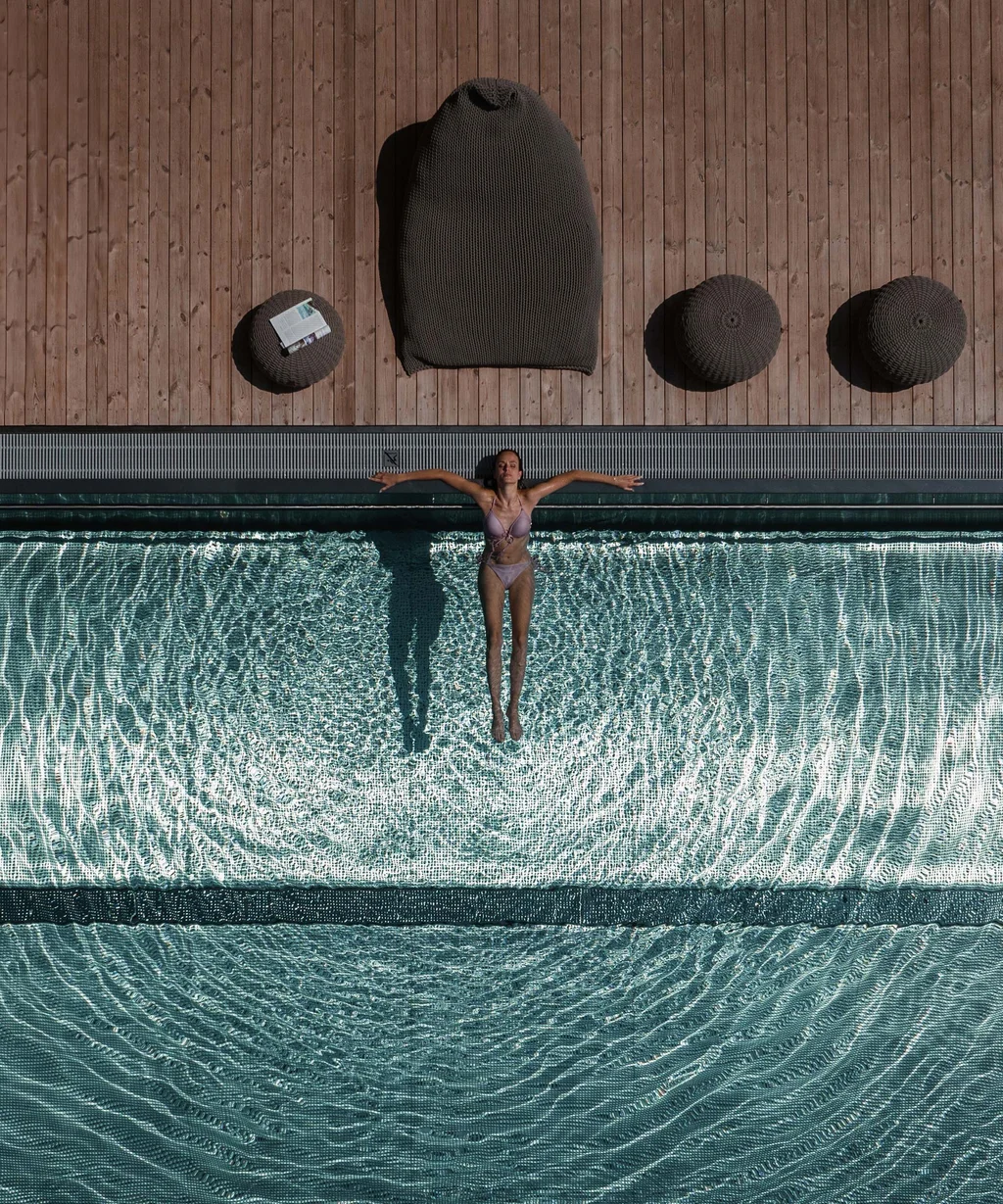 The NILS am See near Parndorf: your hotel at Lake Neusiedl Woman relaxing in pool with sun loungers and wooden deck around