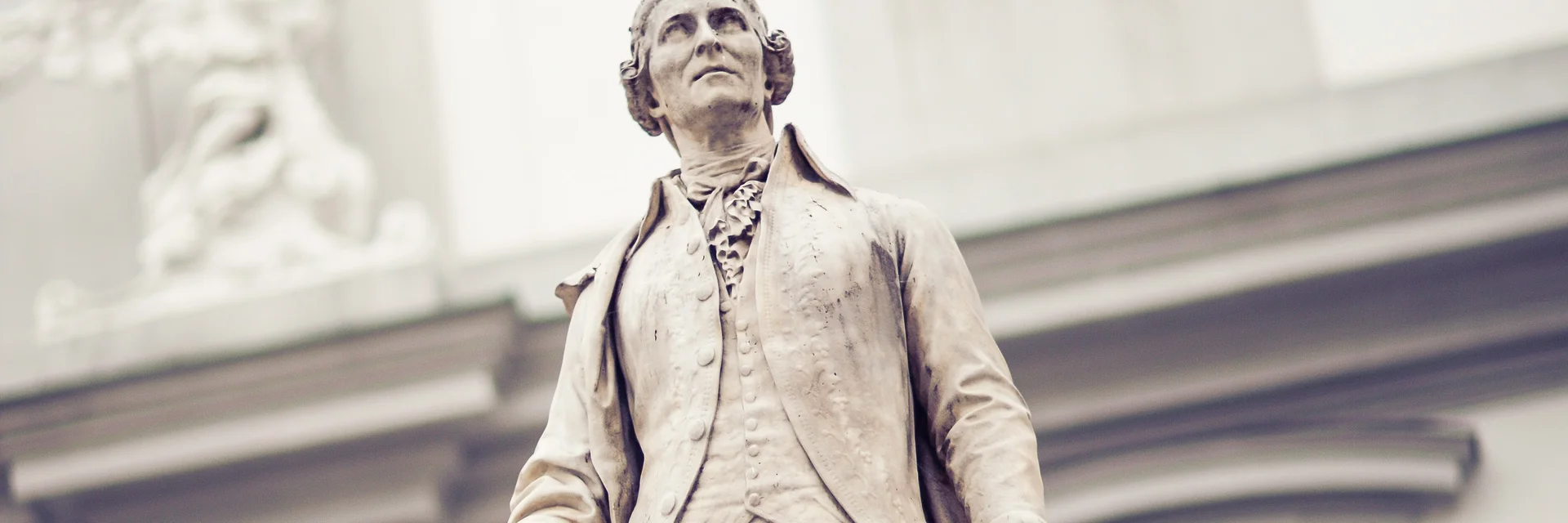 Steinerne Statue eines Mannes mit Tauben auf Kopf und Sockel