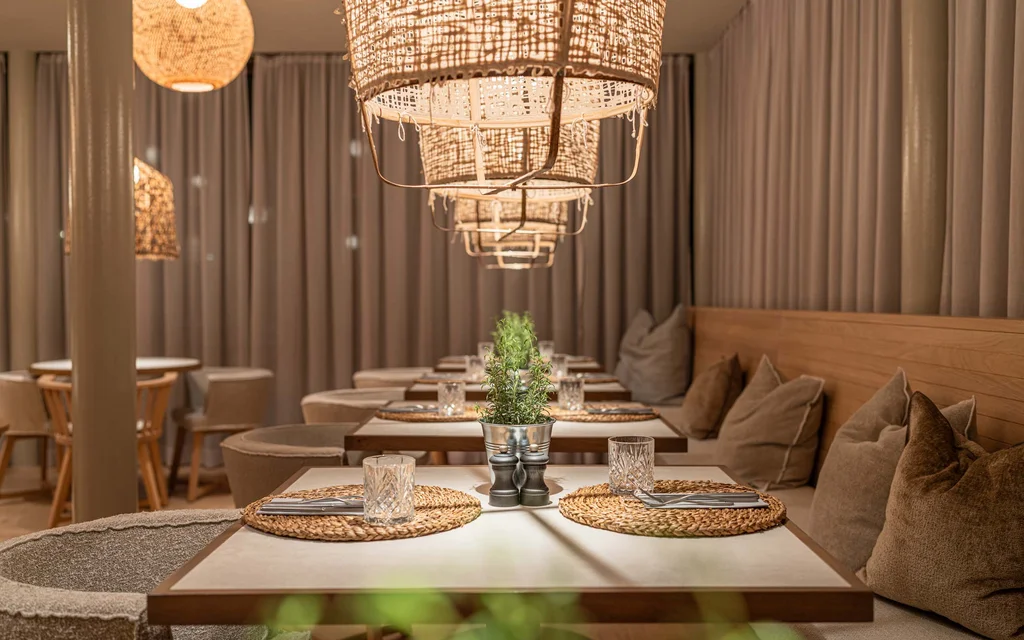 Gemütliches Restaurant mit Holzdekor, weichen Kissen und warmen Lampen