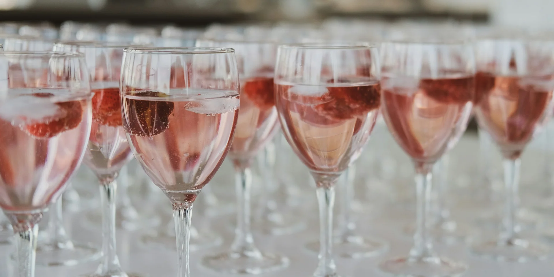 Mehrere Gläser mit roséfarbener Flüssigkeit und Früchten gefüllt